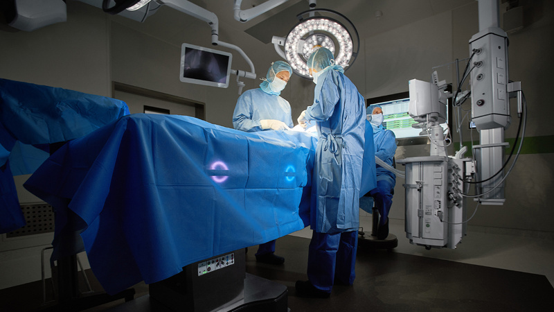 Surgeons and anesthetist performing surgery on a patient lying on an intelligent and connected Maquet Corin OR table