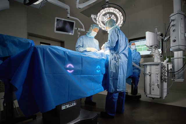 Surgeons and anesthetist performing surgery on a patient lying on an intelligent and connected Maquet Corin OR table