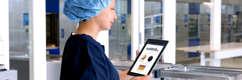 Hospital staff member uses a tablet to review equipment performance and utilization data with Getinge FleetView in a modern hospital environment.