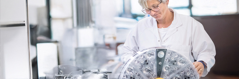 Technician in a lab coat inspecting the Power LED surgical light during production.