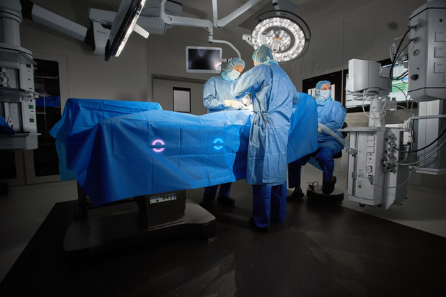 3 people in an OR conducting surgery on a patient lying on an intelligent and connected Maquet Corin OR table