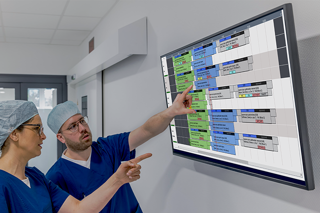 Medical staff in front of bid screen displaying Torin progress updates from different ongoing surgeries